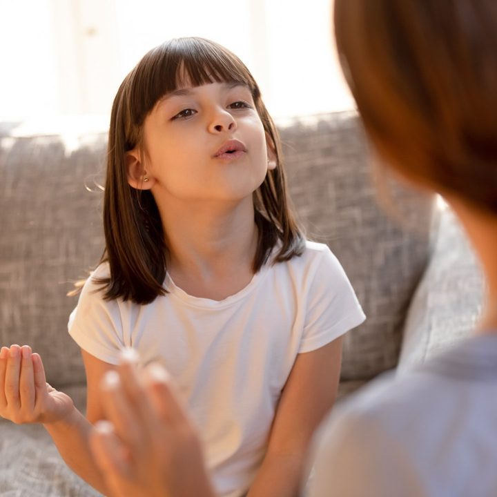 A young girl practising speech sounds with her therapist